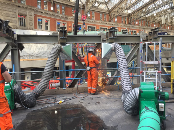 carousel 7 - site operative welding inside a train station with a fume extraction kit removing fume at the source to protect workers and the public nearby
