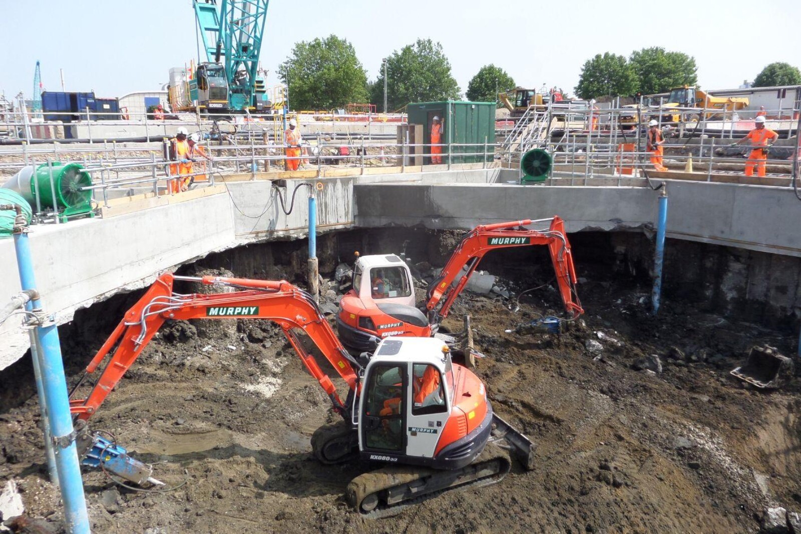 2 VENTEX Axial Fan 1250S on the edge of a small shaft whilst excavation takes place below and 3 workmen line the edge of the shaft being dug_