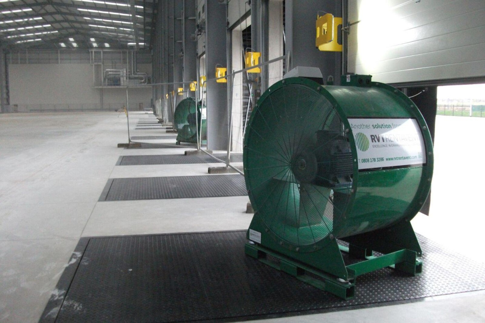 VENTEX Axial Fan 1250S in an industrial warehouse by a shutter slightly open to help force fresh air around the unit